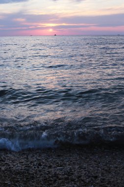 Denizde parlak gün batımı hava ve su dar bir kıyı şeridi çok, su yakın şafak gökyüzünde güneş renkleri bir degrade