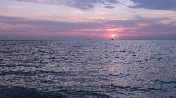Denizde parlak gün batımı hava ve su dar bir kıyı şeridi çok, su yakın şafak gökyüzünde güneş renkleri bir degrade