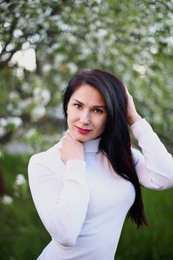 Beyaz bir balıkçı bahar çiçekli leylak ve elma ağaçları uzun siyah saçlı genç gülümseyen kadın