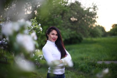 Beyaz bir balıkçı bahar çiçekli leylak ve elma ağaçları uzun siyah saçlı genç gülümseyen kadın