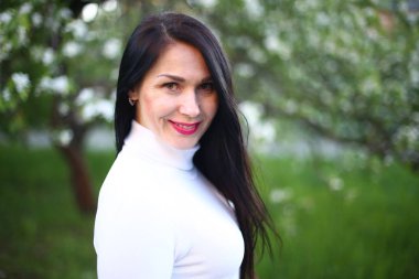 Beyaz bir balıkçı bahar çiçekli leylak ve elma ağaçları uzun siyah saçlı genç gülümseyen kadın