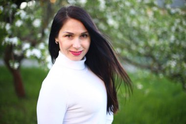 Beyaz bir balıkçı bahar çiçekli leylak ve elma ağaçları uzun siyah saçlı genç gülümseyen kadın