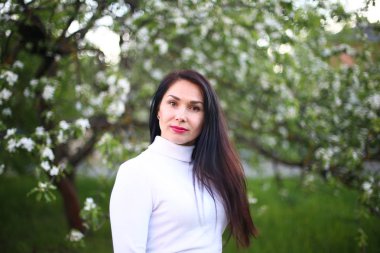 Beyaz bir balıkçı bahar çiçekli leylak ve elma ağaçları uzun siyah saçlı genç gülümseyen kadın