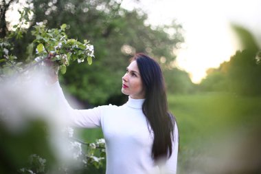 Beyaz bir balıkçı bahar çiçekli leylak ve elma ağaçları uzun siyah saçlı genç gülümseyen kadın