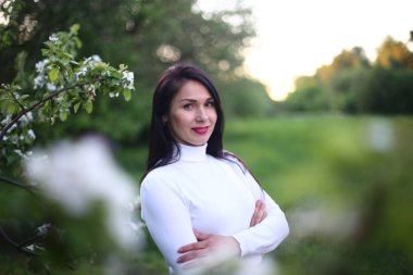 Beyaz bir balıkçı bahar çiçekli leylak ve elma ağaçları uzun siyah saçlı genç gülümseyen kadın