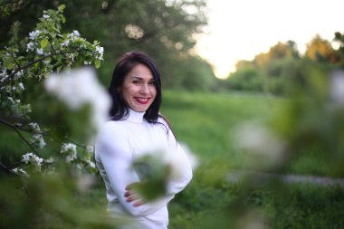 Beyaz bir balıkçı bahar çiçekli leylak ve elma ağaçları uzun siyah saçlı genç gülümseyen kadın