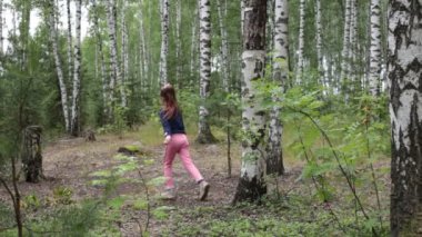 Sekiz yaşında bir kız yaz güneşli bir ormanda yürüyor.