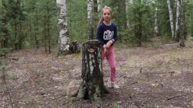 Sekiz yaşında bir kız yaz güneşli bir ormanda yürüyor.