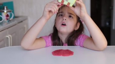 Sekiz yaşındaki kız çocuklar arasında popüler olan sümüklü şekerle oynuyor.