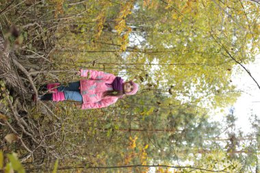 Ormanda sonbahar yürüyüşü yapan bir kız.