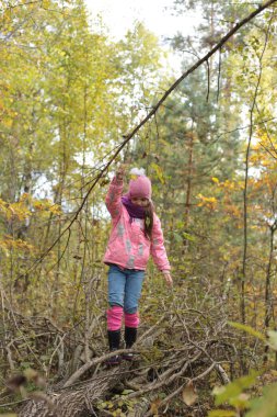 Ormanda sonbahar yürüyüşü yapan bir kız.