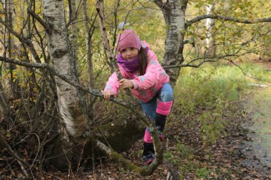 Ormanda sonbahar yürüyüşü yapan bir kız.