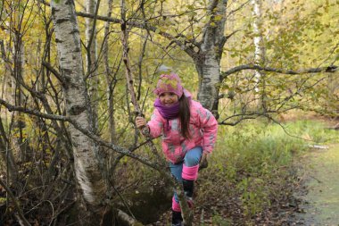 Ormanda sonbahar yürüyüşü yapan bir kız.
