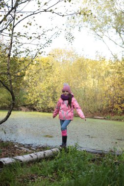 Ormanda sonbahar yürüyüşü yapan bir kız.