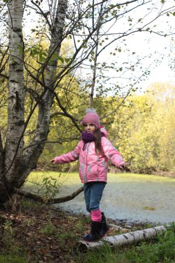Ormanda sonbahar yürüyüşü yapan bir kız.