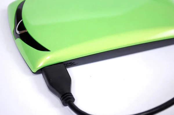 The external computer hard drive of information storage with a wire of light green color on a white background. The hard drive of storage of digital information it is isolated.