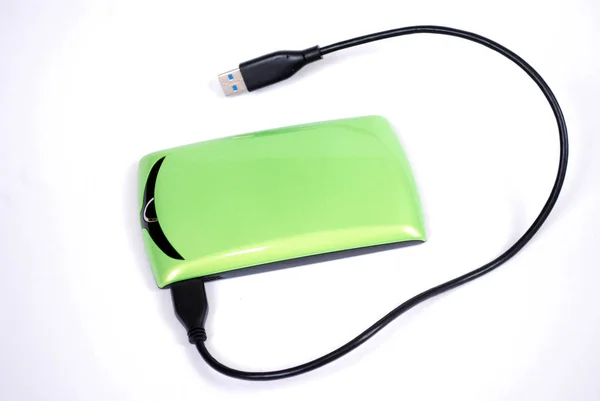 The external computer hard drive of information storage with a wire of light green color on a white background. The hard drive of storage of digital information it is isolated.
