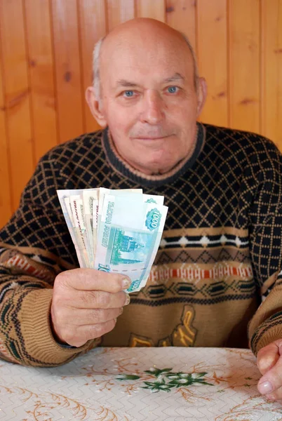 达查的祖父坐在一张桌子旁 手里拿着纸条 老人坐在桌旁 手里拿着钱 — 图库照片