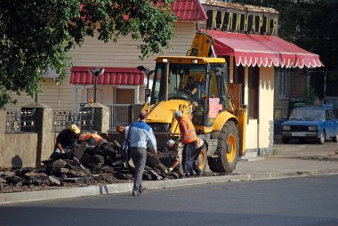 Kurchatov'un Akademika Caddesi'nde yol çalışması. İşçiler kaldırılan asfaltı traktörün bir kovasında istifleyin.)