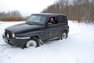 Genç adam kışın tarlada kar üzerinde cip sürmek