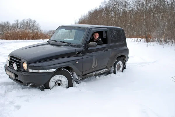 Genç adam kışın tarlada kar üzerinde cip sürmek