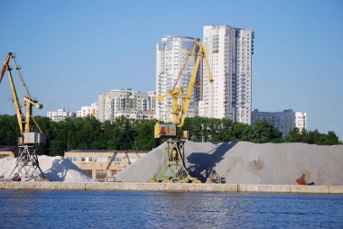 Mavnayükleme için endüstriyel vinç Kuzey Nehri İstasyonu'nda Khimki rezervuar kıyısında kum ve çakıl büyük yığınları arka planda duruyor. şehir Moskova. Rusya.