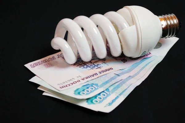 Energy-saving light bulb and money. Paper bills. Saving money.