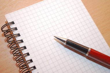 Masanın üzerinde defter ve kalem, yakın çekim.