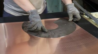 Usta kalaycı, bakır levhadan yapılmış boş bir şablona göre geleceğin ürününün detaylarını çiziyor. Üretim. El yapımı iş.