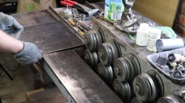 Usta Tinsmith gelecekteki ürünü galvanize çelikten bir katlama makinesine sarar. Üretim. El yapımı iş.