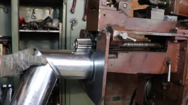 Usta Tinsmith galvanize çelikten yapılma olukta yuvarlanıyor. Üretim. El yapımı iş.