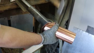 Usta kalaycı, bakır bir borunun bağlantı kilidini elle açıyor. Üretim. El yapımı iş.