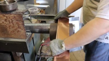 Usta Tinsmith boruya eğiliyor ve bakırdan yapılmış gelecekteki ürünün detaylarına giriyor. Üretim. El yapımı iş.