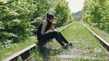 Terk edilmiş bir demiryolu raylar üzerinde fiziksel egzersizler gerçekleştirdikten sonra siyah elbiseli Genç esmer aittir
