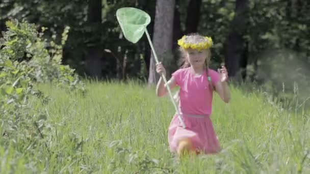 Ребенок с сеткой бабочки, бегущей по лесной поляне, на голове венка из одуванчиков — стоковое видео