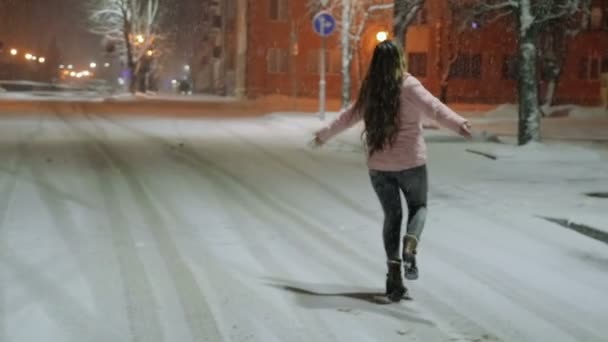 Портрет молодої щасливої жінки в зимовому місті. Дівчина йде по вулиці і насолоджується снігом — стокове відео