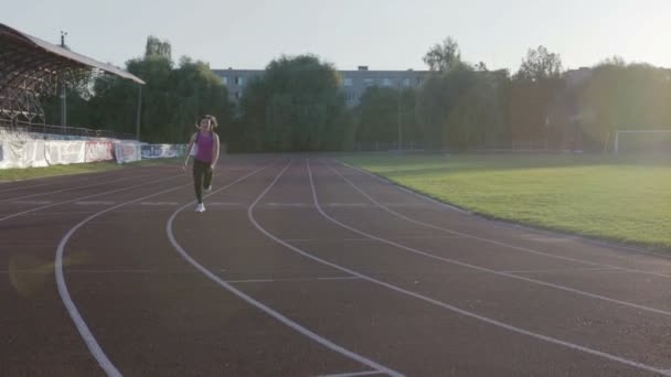 Bella ragazza del fitness che corre attraverso lo stadio. Giovane atleta in allenamento — Video Stock