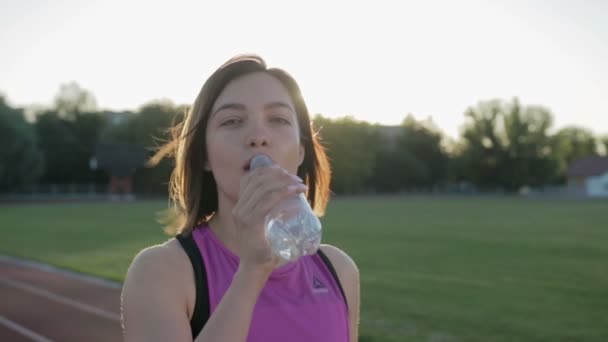 Mooie fitness meisje drinking water uit een fles tijdens een training — Stockvideo