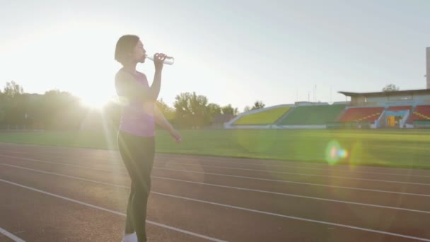 Hermosa chica de fitness beber agua de una botella durante un entrenamiento — Vídeo de stock