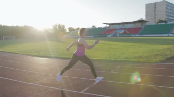 Hermosa chica de fitness entrena en el estadio. Un joven atleta corre los obstáculos — Vídeos de Stock