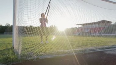 Güzel fitness kız stadyumda eğitiyor. Genç bir atlet futbol gol alanında Trx döngüler ile nişanlandı
