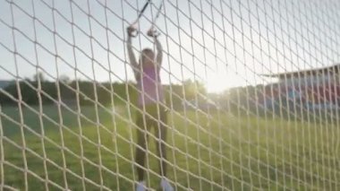 Güzel fitness kız stadyumda eğitiyor. Genç bir atlet futbol gol alanında Trx döngüler ile nişanlandı. Steadicam atış