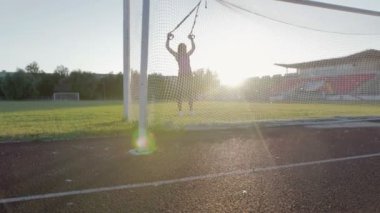 Güzel fitness kız stadyumda eğitiyor. Genç bir atlet futbol gol alanında döngüler ile nişanlandı