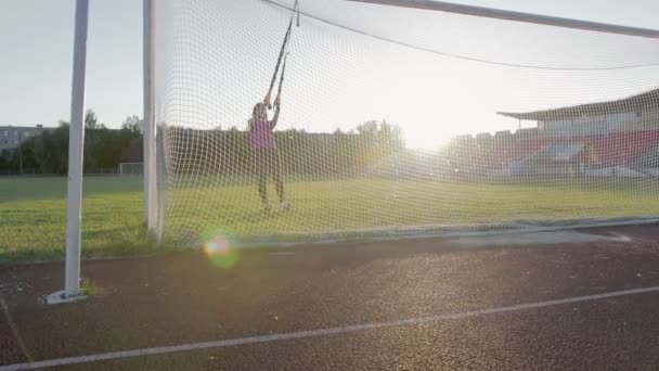 Hermosa chica de fitness entrena en el estadio. Un joven atleta se dedica a bucles en el campo en el gol de fútbol — Vídeos de Stock