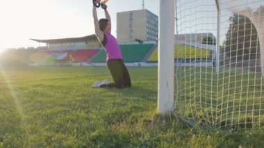 Güzel fitness kız stadyumda eğitiyor. Genç bir atlet futbol gol alanında döngüler ile nişanlandı