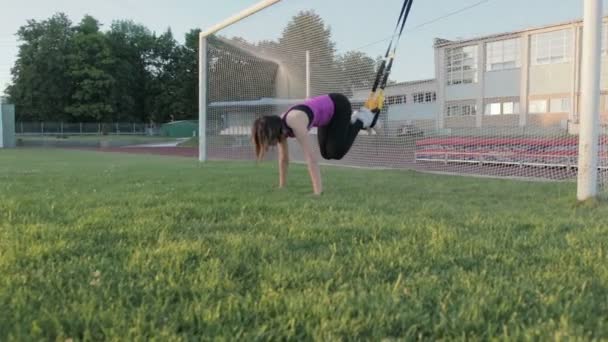 Hermosa chica de fitness entrena en el estadio. Un joven atleta se dedica a bucles en el campo en el gol de fútbol — Vídeo de stock