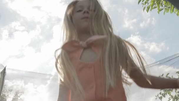 Una hermosa chica salta alto en una cama elástica para niños — Vídeos de Stock