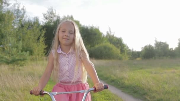 Hermosa, niña monta una bicicleta para niños, bicicleta para niños — Vídeo de stock