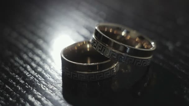 Wedding rings lie on the black table — Stock Video