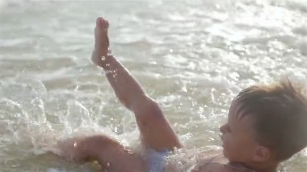 Små, sprallig, glad pojke, son simning i havet. Han kör och hoppar och stänk och faller i vattnet. — Stockvideo